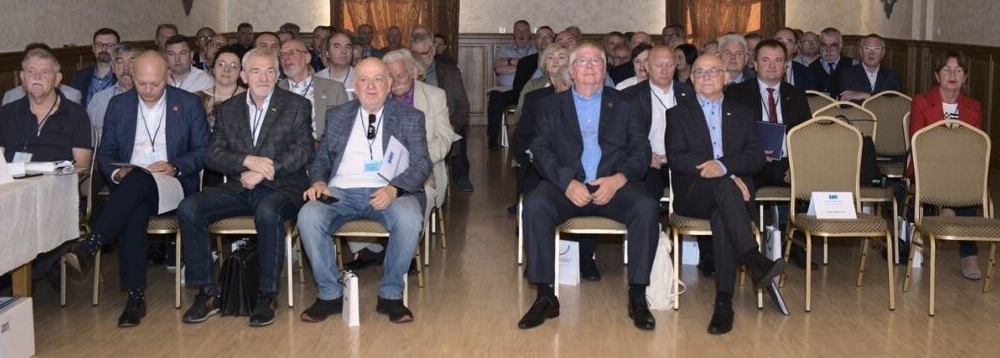 grupa siedzących ludzi spogląda w stronę kamery